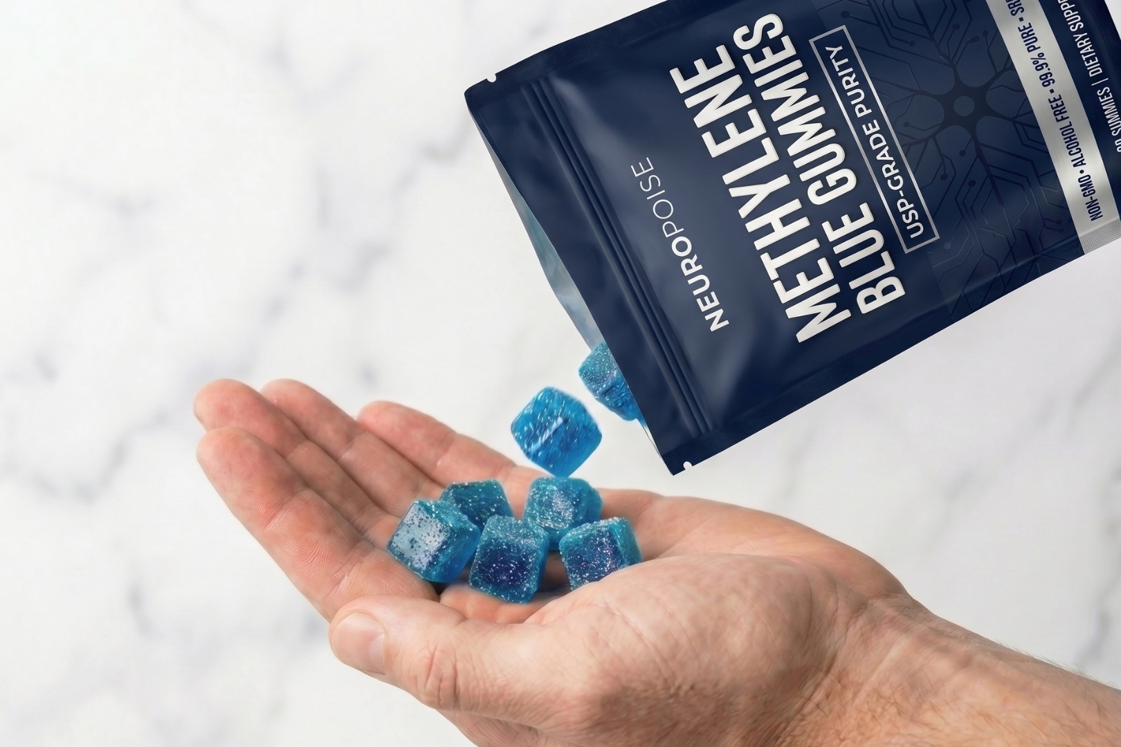 Close-up of blue cube-shaped gummies being poured from a dark blue pouch into a person's open hand.