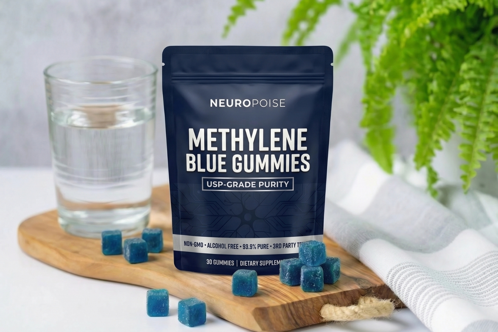A pouch of NeuroPoise Methylene Blue Gummies with several gummies on a wooden board next to a glass of water.