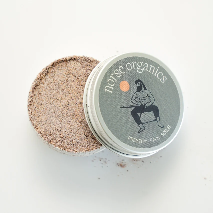 An open tin of Norse Organics Premium Face Scrub showing the brown, grainy texture of the product.