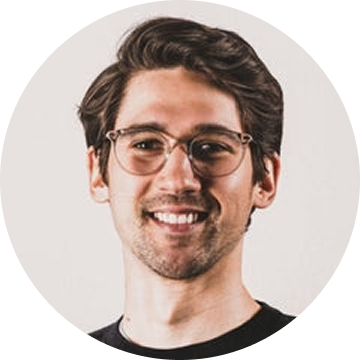 Man with glasses smiling against a plain background.