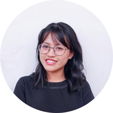 A person with glasses and black hair, wearing a black shirt, smiling at the camera.