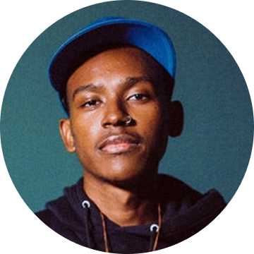 Person wearing a blue cap and black hoodie against a green background.