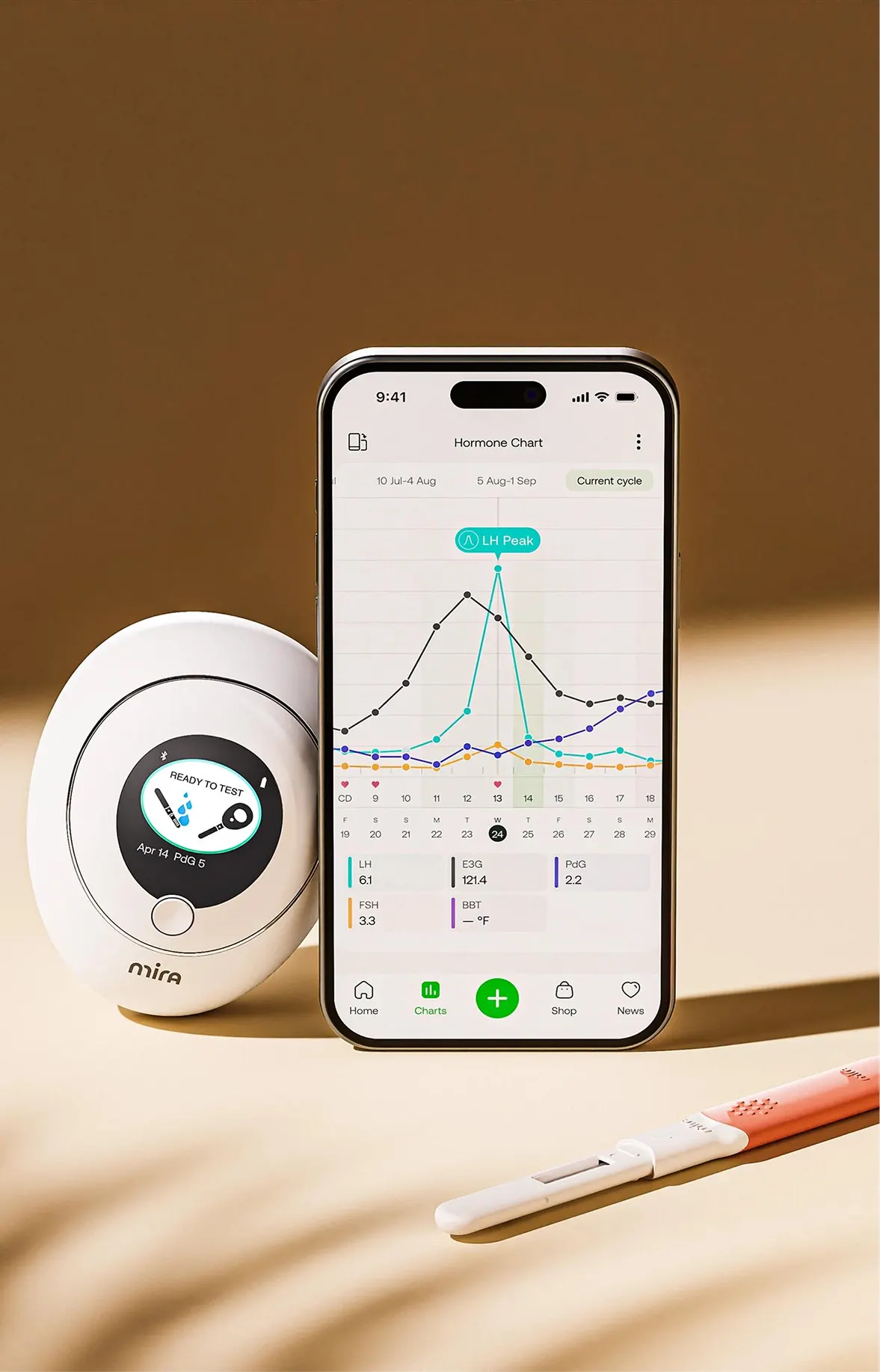 A Mira fertility tracking device and test stick next to a smartphone displaying a hormone chart app.