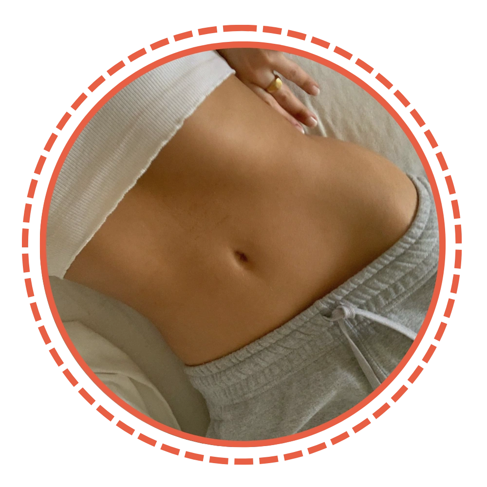 A close-up of an abdomen wearing a white top and grey sweatpants.