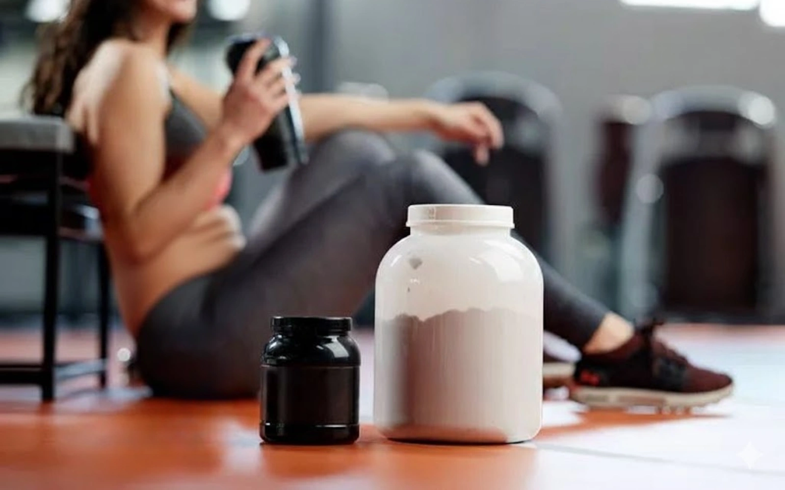 Two jars on a gym floor with a person holding a shaker in background.