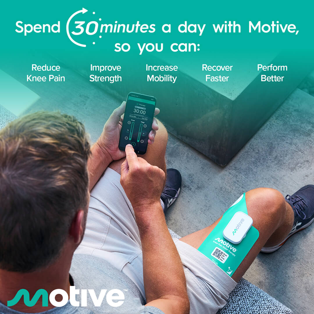 A man uses a smartphone to control a Motive therapy device attached to his thigh.