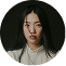 A circular portrait of a young East Asian woman with long dark hair against a dark background.