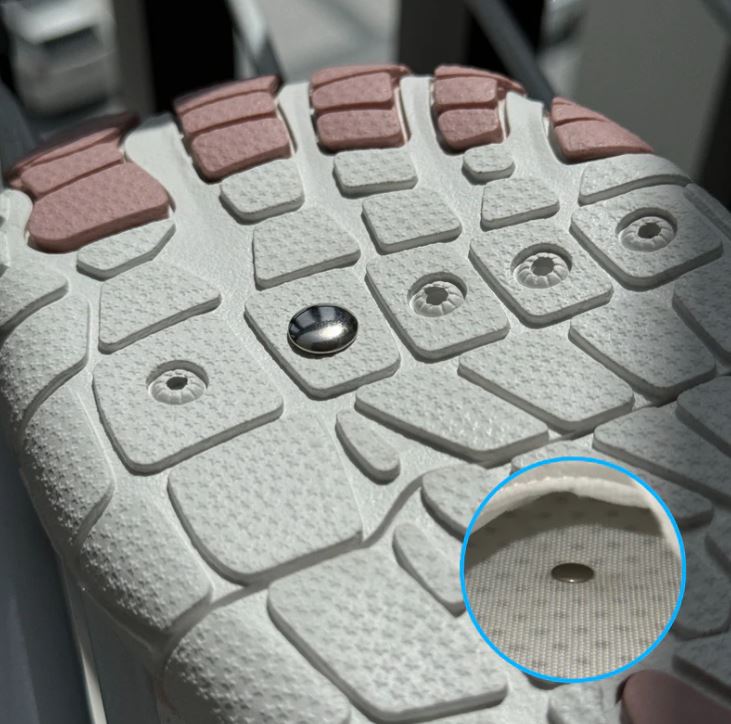 Close-up of a shoe sole with a metal screw and textured pattern.