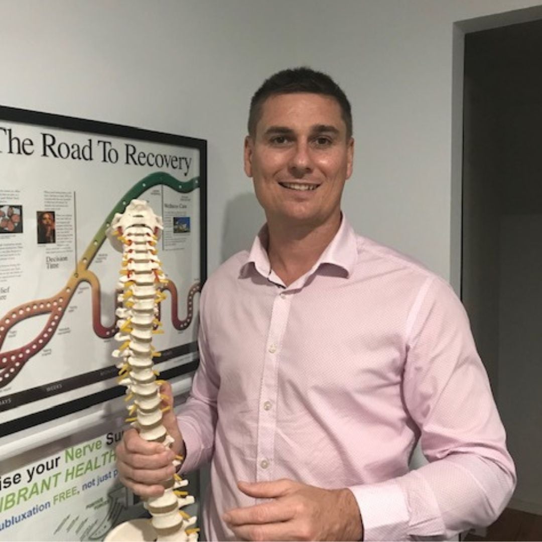 Person holding a spine model next to a recovery poster.
