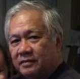 A smiling woman with blonde hair, wearing a lime green sweatshirt, stands in a garden.