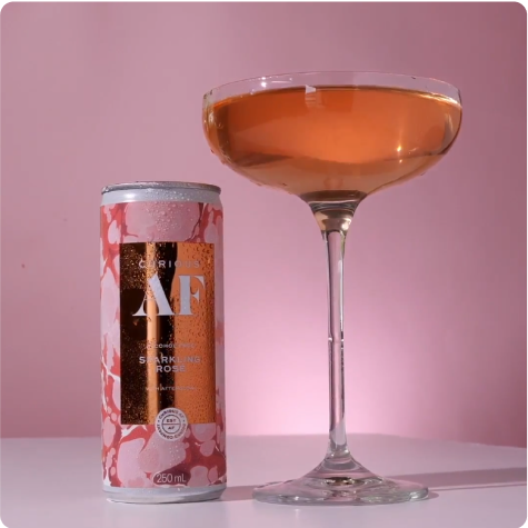 A can and glass of sparkling rosé against a pink background.