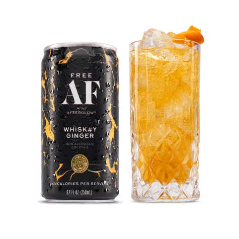 Can of non-alcoholic whisky ginger next to a glass with ice and an orange garnish.