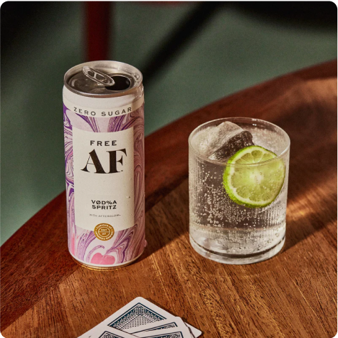 A can of Free AF Vodka Spritz and a glass with ice and lime on a table.