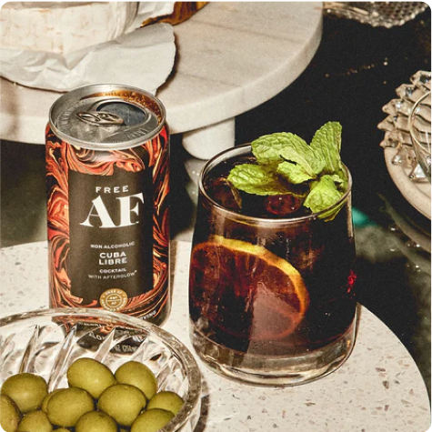 Non-alcoholic Cuba Libre cocktail with mint, beside a can and olives.