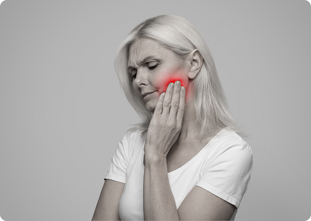 Woman holding her cheek in pain, with a red highlight on the jaw area.