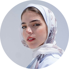 Woman wearing a floral-patterned headscarf, looking at the camera against a light background.