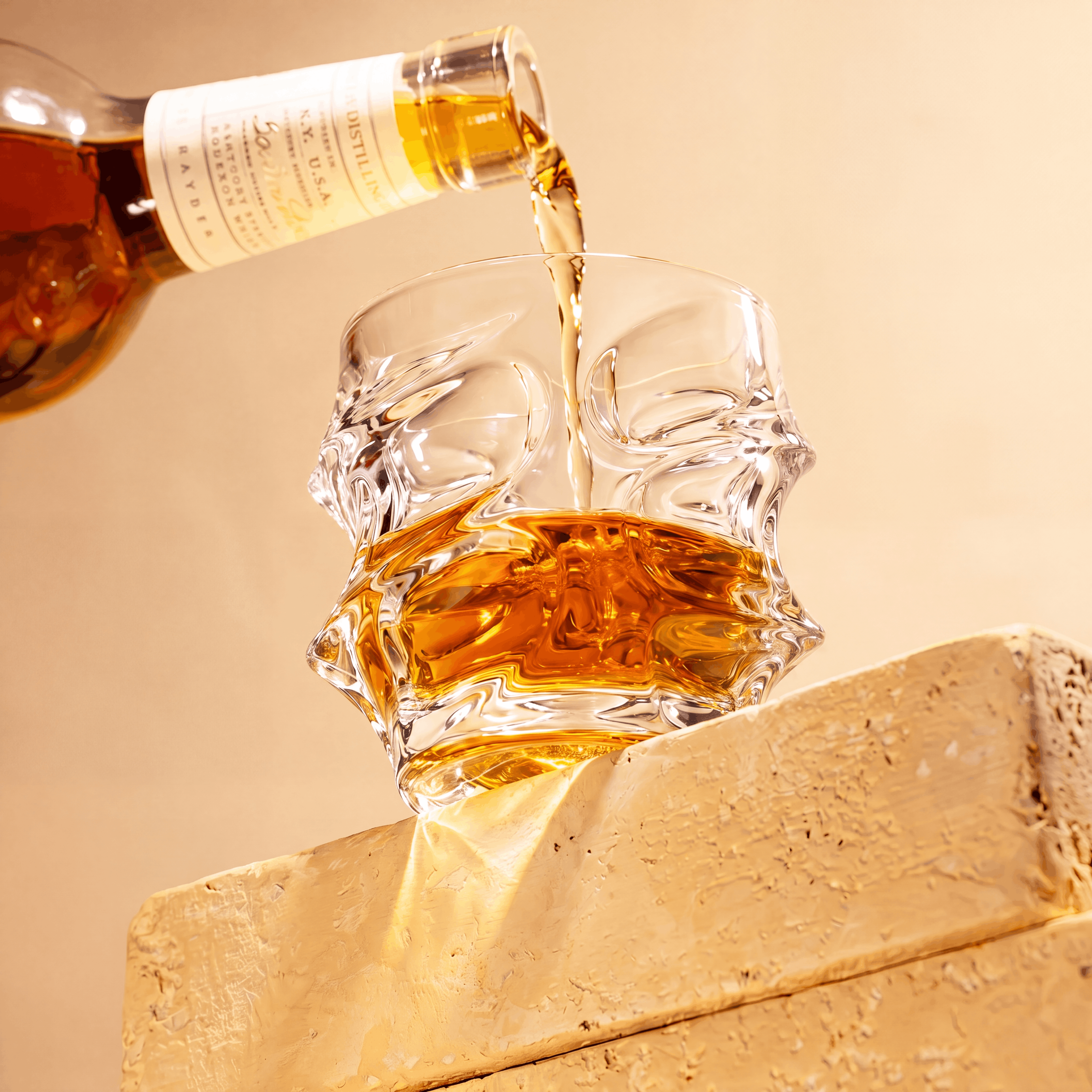 An amber liquid being poured from a bottle into a clear, skull-shaped glass on a block.