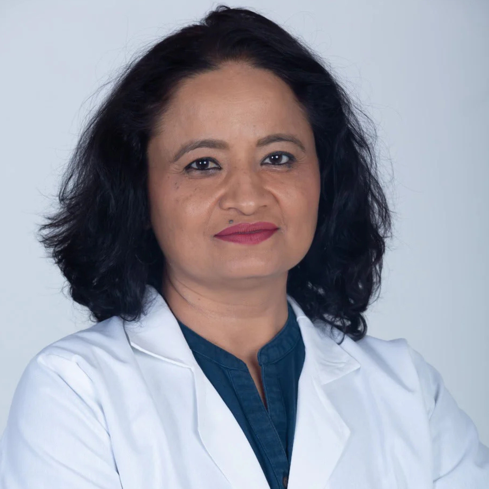 Person in a white coat with a neutral expression against a plain background.