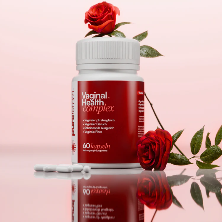 Bottle of vaginal health capsules with red roses and pills on a reflective surface.