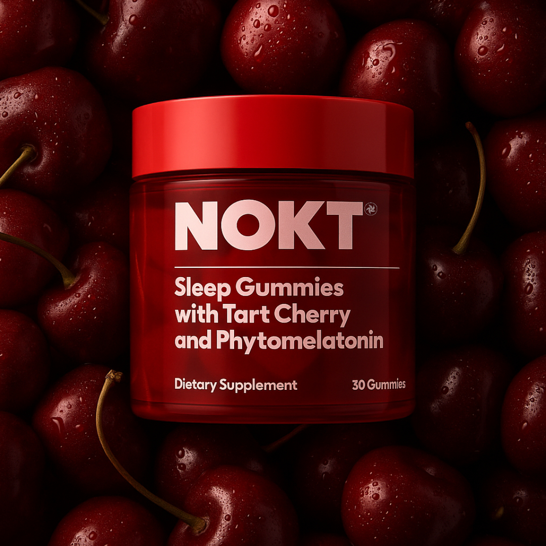 Red jar of sleep gummies surrounded by fresh cherries.