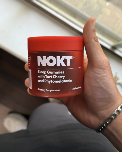 Hand holding a red container of NOKT Sleep Gummies.