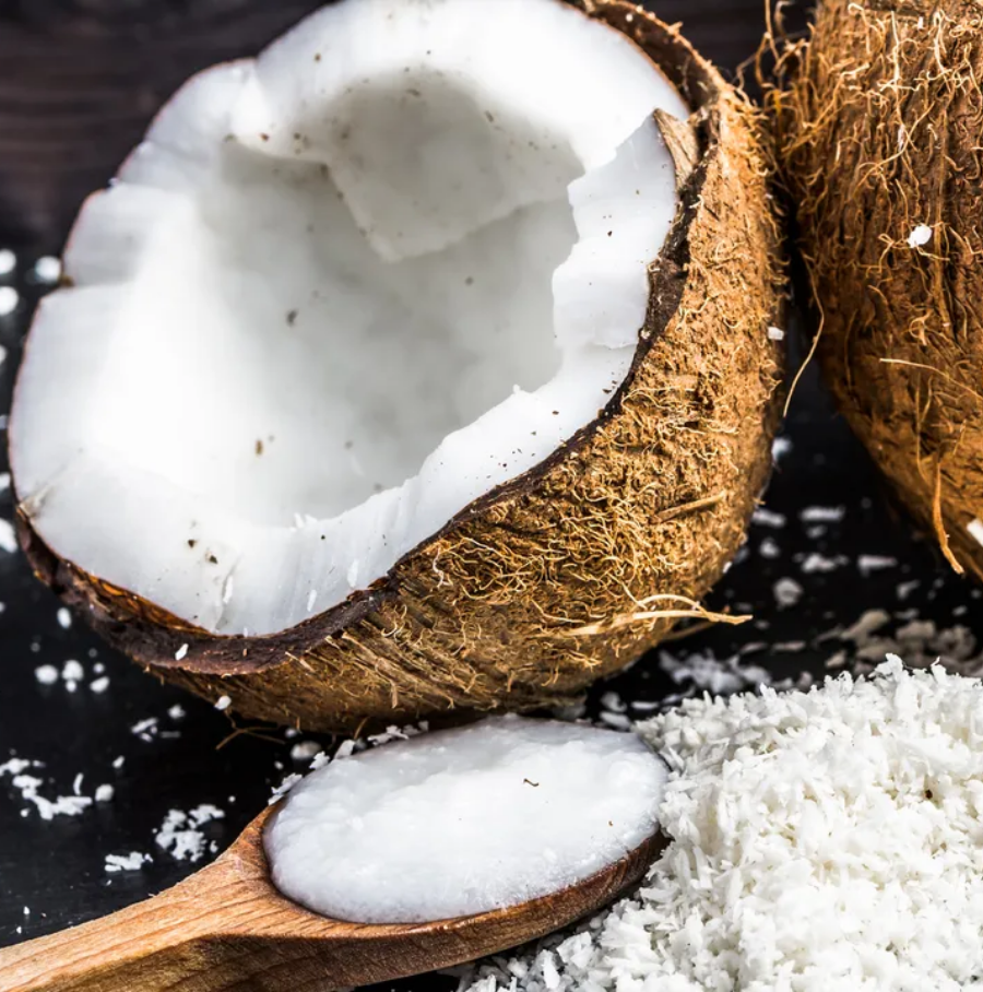 Person applying lotion on leg, sitting on a wooden stool in a bathroom.