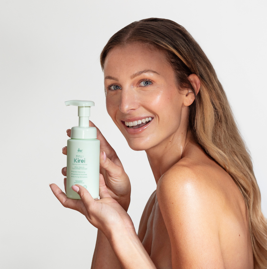 Person holding a skincare product near their face and shoulder.