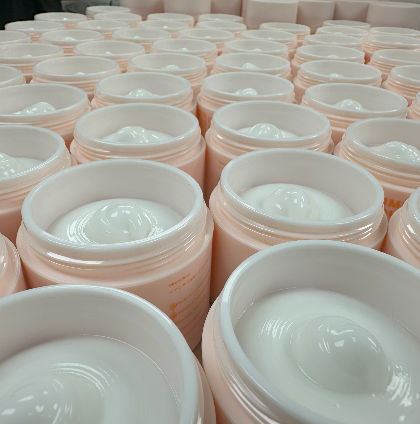 Rows of open jars filled with white cream.