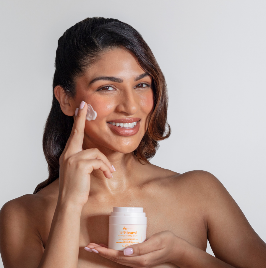 Person holding a skincare product near their face and shoulder.
