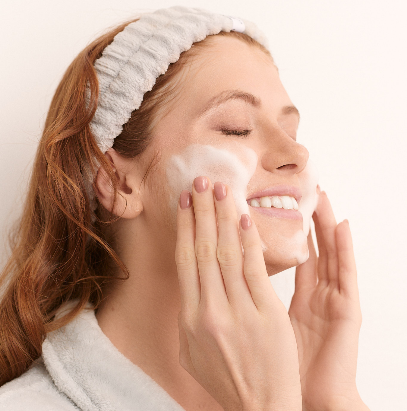 Person holding a bottle of 'rhode' skincare product near their face.