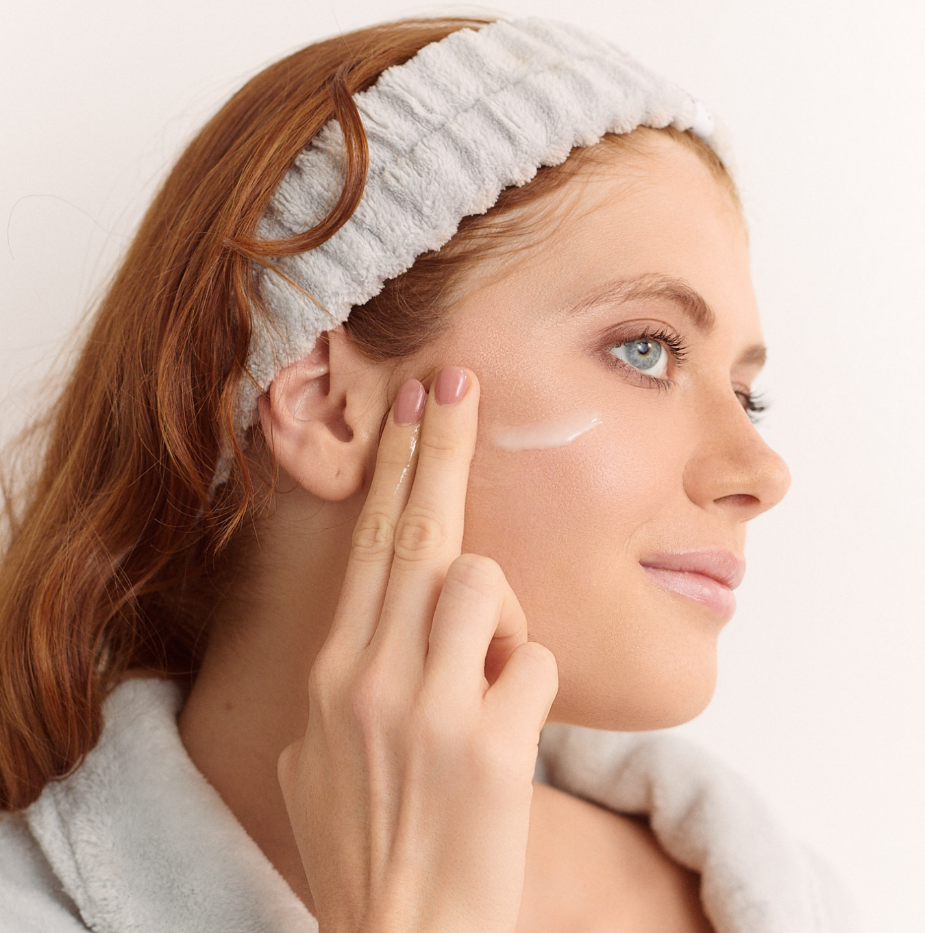 Person applying cream to face with a headband.