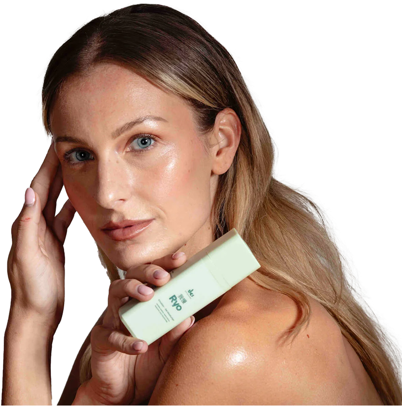 Person holding a skincare product near their face and shoulder.