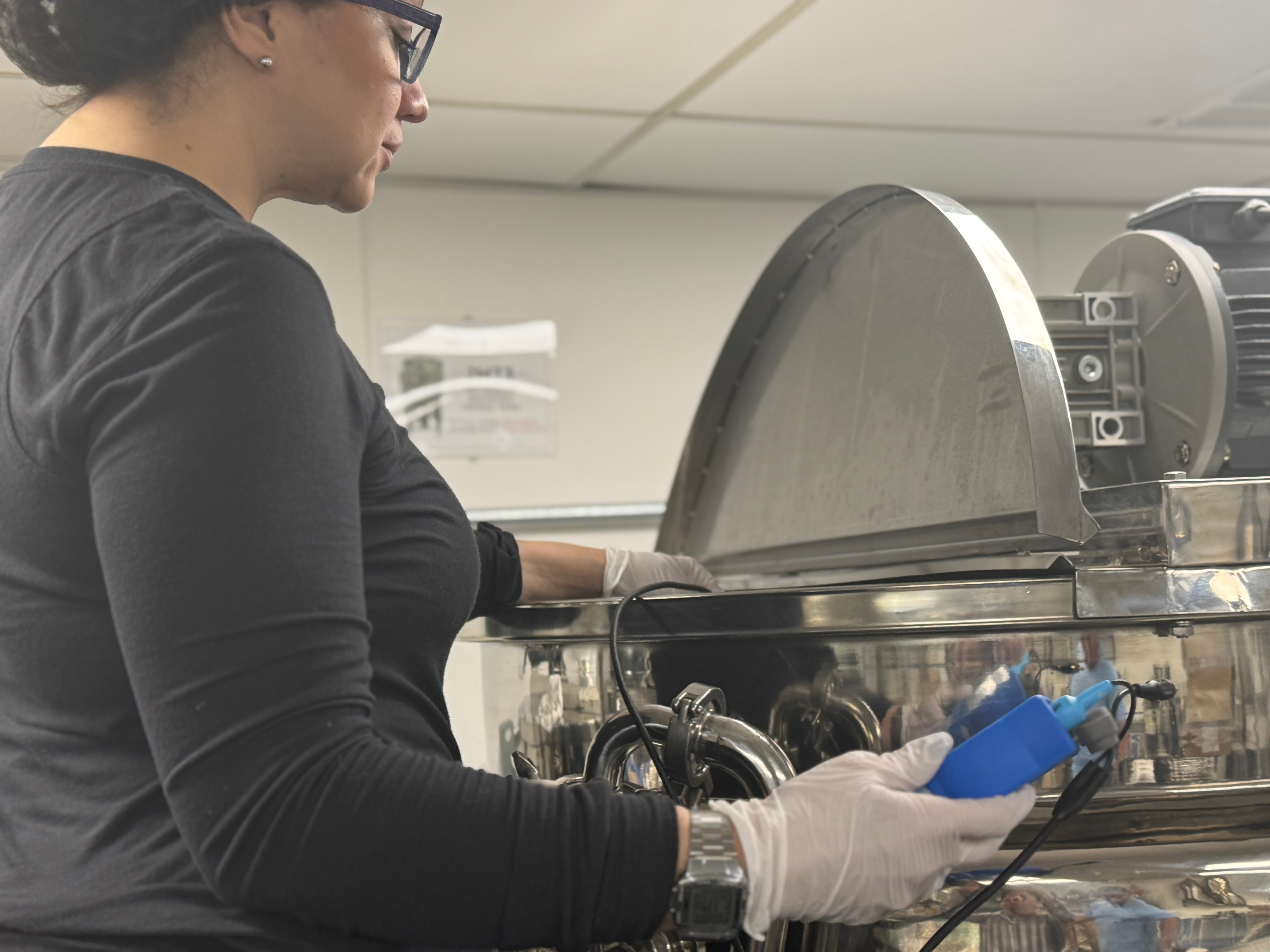 Person wearing gloves working with industrial machinery.