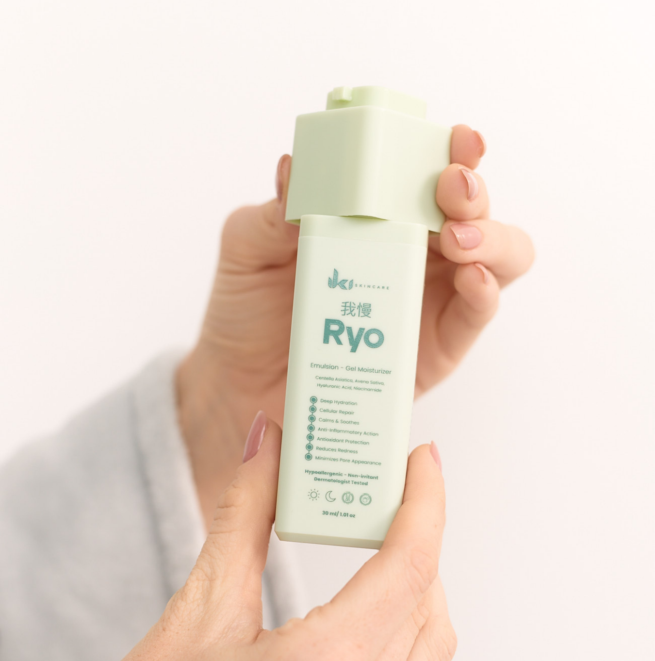 Hand holding a green skincare product bottle labeled 'Ryo'.