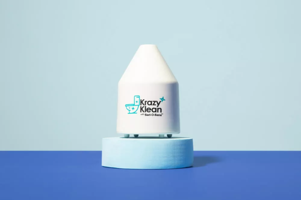 White Krazy Klean device on blue pedestal against a light blue background.