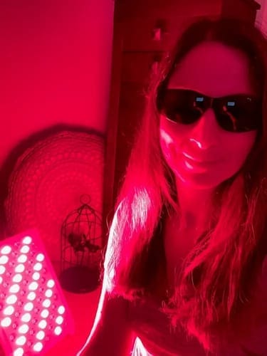Person wearing sunglasses in a room illuminated by red light.