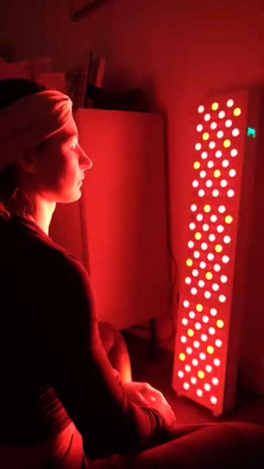 A person sits in profile before a tall panel of glowing red and yellow lights.