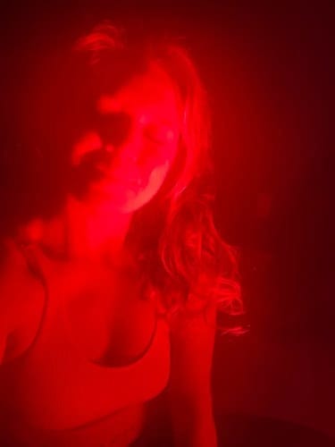 Person bathed in red light, with long hair and closed eyes.