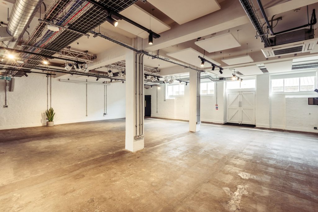 Spacious empty room with industrial ceiling and large windows.