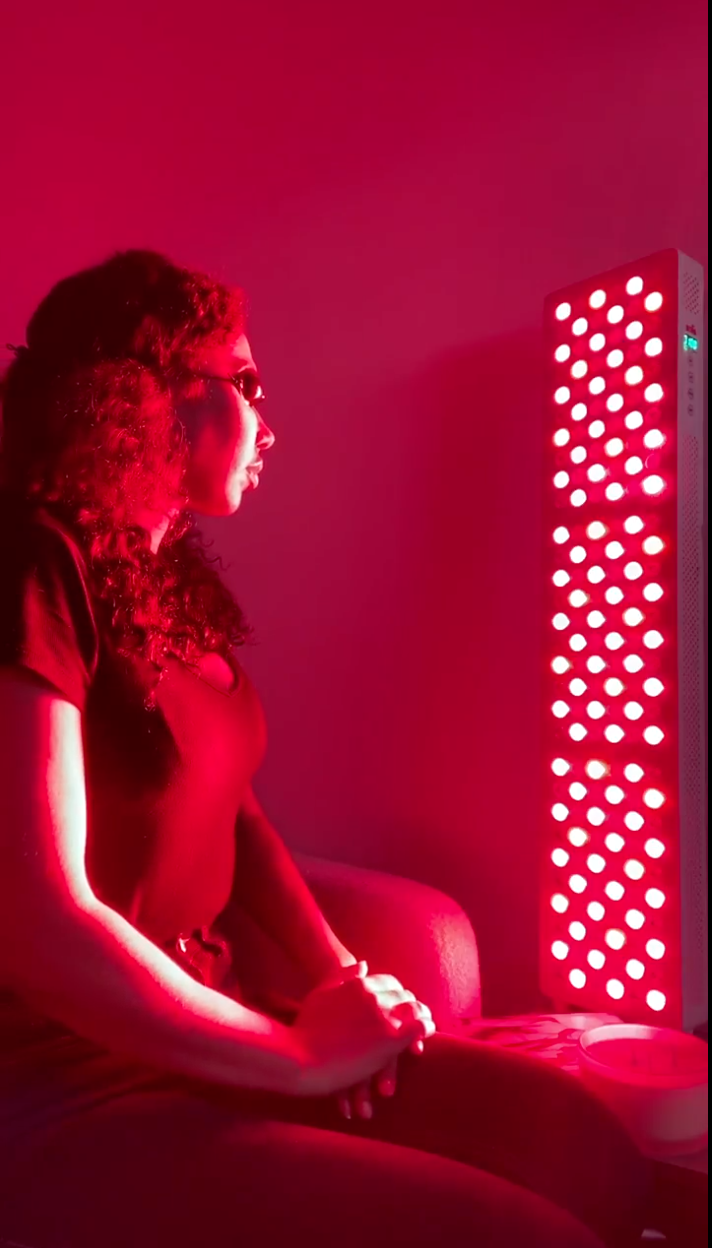 Person sitting in front of a red light therapy panel.