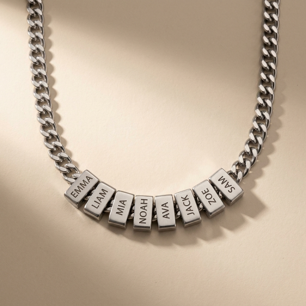 A silver curb chain necklace with multiple rectangular beads, each engraved with a name.