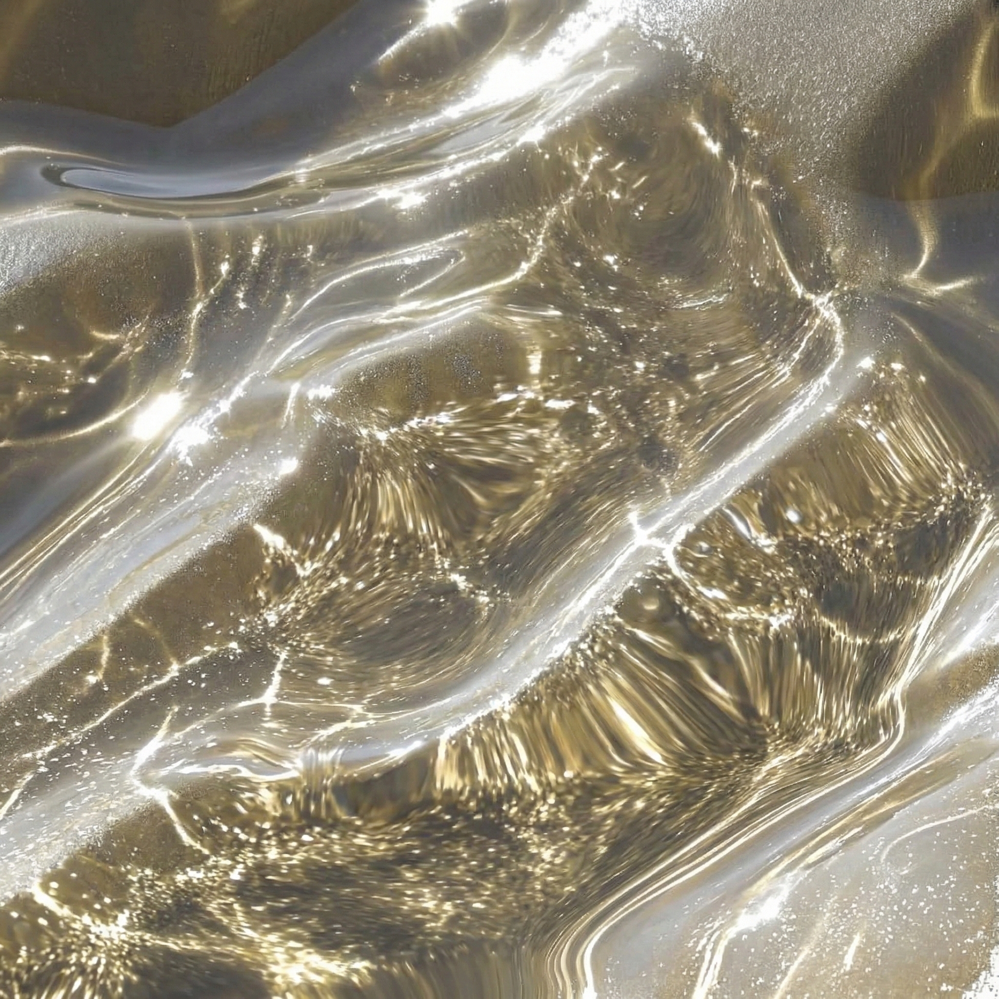 An abstract close-up of a shimmering liquid surface with golden and silver light reflections.