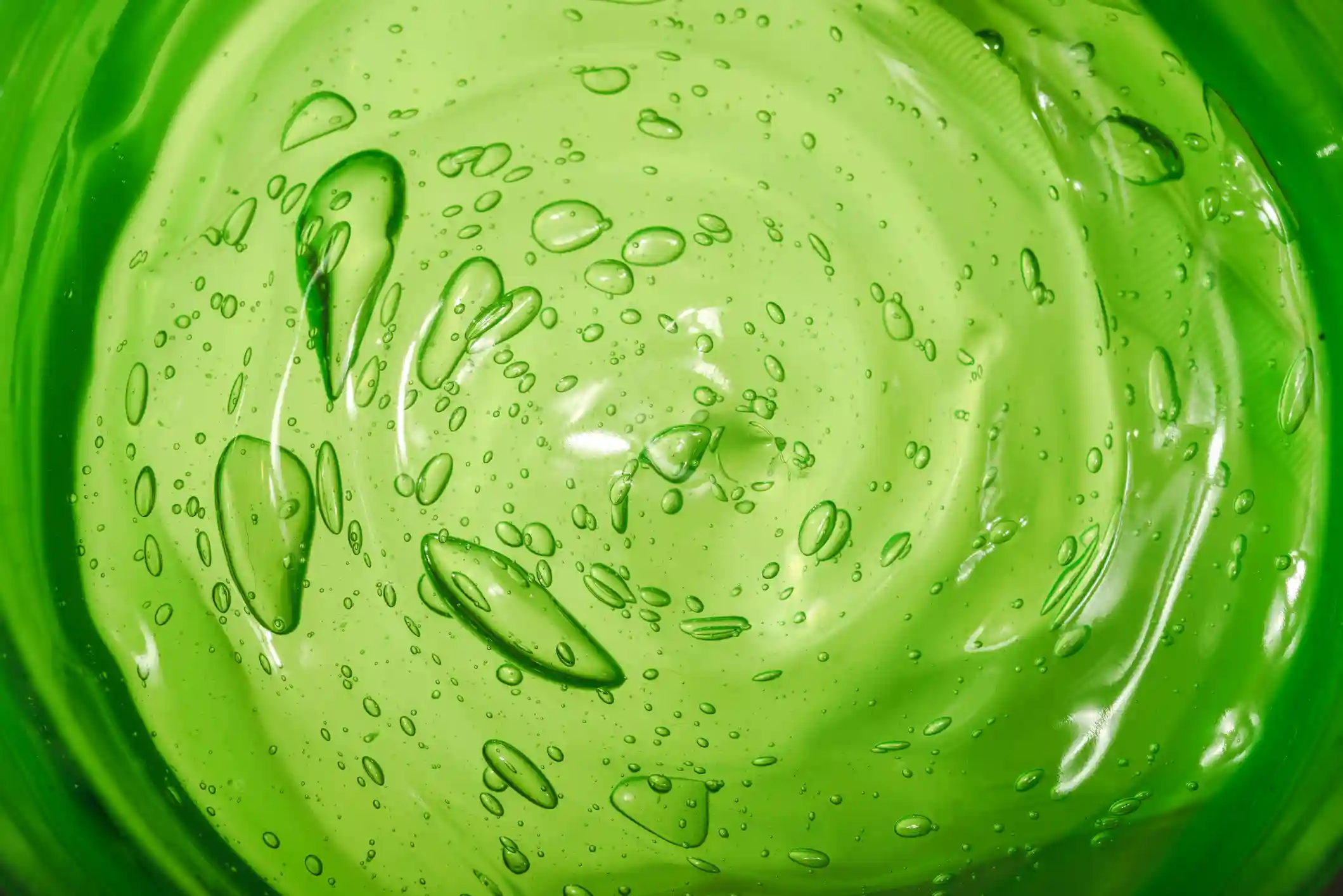 A close-up, top-down view of a swirling, bright green transparent gel with many air bubbles.