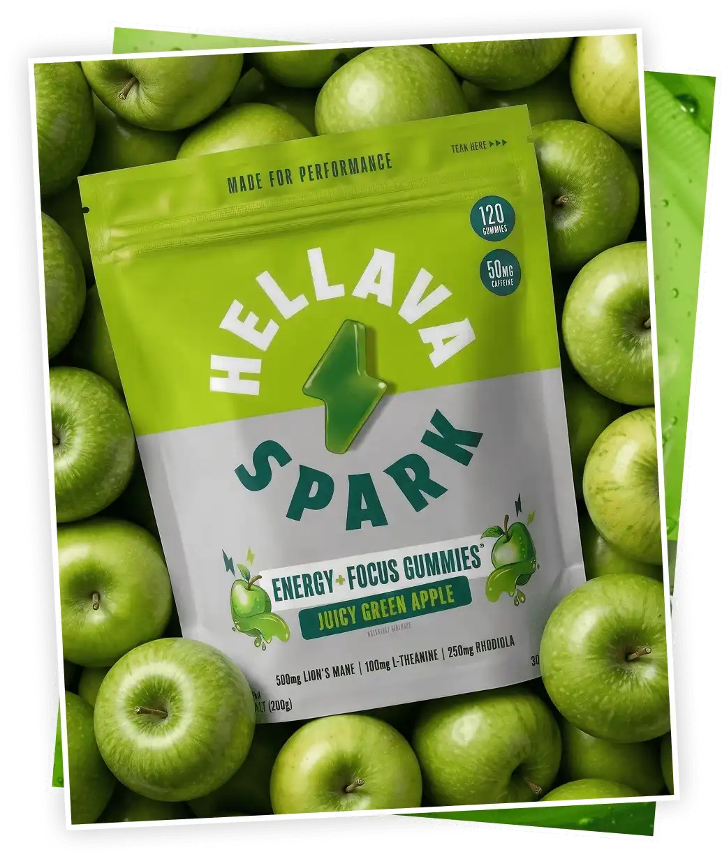 A pouch of Hellava Spark Juicy Green Apple energy gummies sits on a bed of fresh green apples.