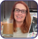 Person holding a glass of iced coffee and a closed book.