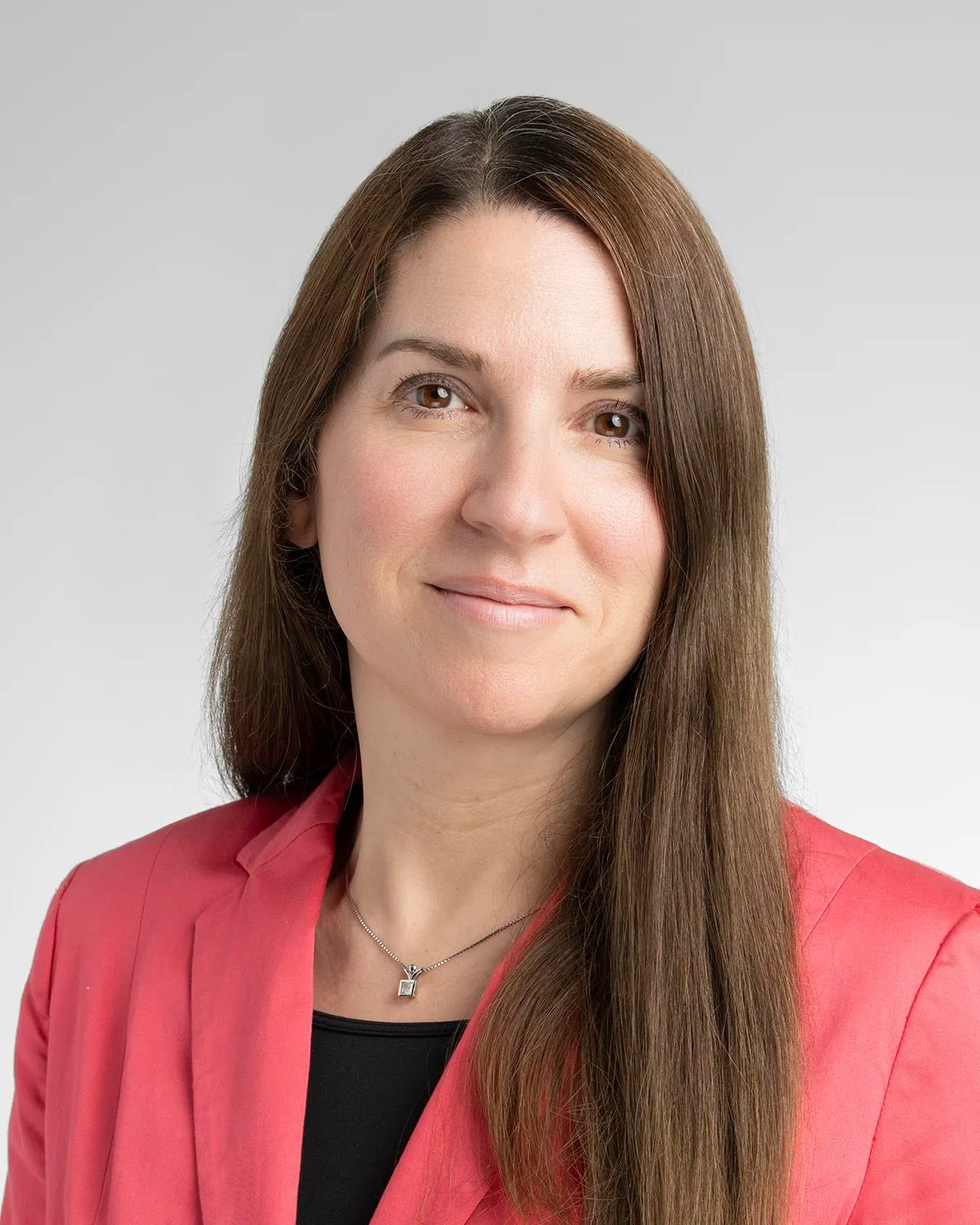 Person in a red blazer with long brown hair, smiling slightly.