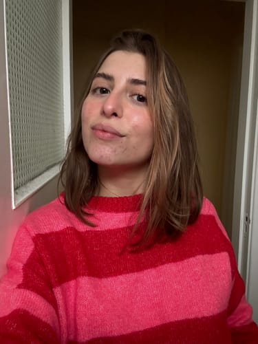 Person wearing a red and pink striped sweater, standing indoors.