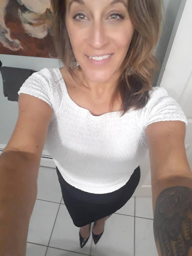 Woman in white top and black skirt taking a selfie.