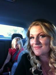 Woman and child sitting in a car, smiling at the camera.