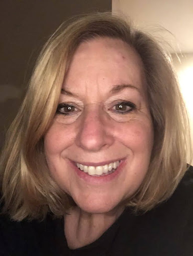 A person smiling with shoulder-length blonde hair.